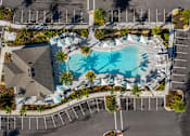 Thumbnail 29 of 29 - An aerial view of a swimming pool surrounded by palm trees and a parking lot.