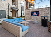 Thumbnail 30 of 45 - A patio with a couch and a TV on a stone wall.