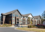 Thumbnail 9 of 45 - A large apartment complex with a car parked in front.