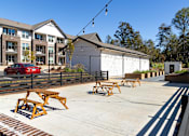 Thumbnail 36 of 45 - A sunny day at a park with picnic tables and a red car parked in the background.