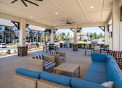 Thumbnail 28 of 45 - A patio with blue couches and a ceiling fan.