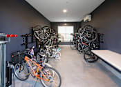Thumbnail 27 of 45 - A room with a white bench and a wall-mounted bike rack holding several bicycles.