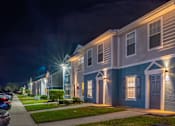 Thumbnail 12 of 15 - A row of townhouses are lit up at night.