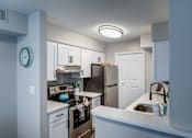 Thumbnail 11 of 20 - A kitchen with a white counter and a clock on the wall.