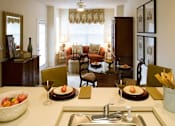 Thumbnail 11 of 23 - A kitchen with a table set for two with a bowl of fruit on it.