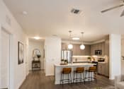 Thumbnail 6 of 35 - A modern kitchen with a bar area and a ceiling fan.