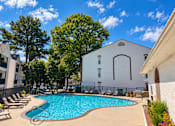 Thumbnail 2 of 20 - A pool surrounded by trees and a white building.