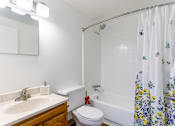 Thumbnail 8 of 18 - A white bathroom with a floral shower curtain.