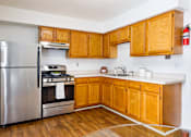Thumbnail 2 of 18 - A kitchen with wooden cabinets and a stainless steel refrigerator.