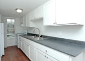 Thumbnail 13 of 18 - A kitchen with white cabinets and a grey countertop.
