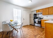 Thumbnail 9 of 18 - A kitchen with a table and chairs in front of a window.