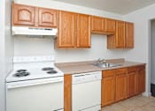 Thumbnail 12 of 18 - A kitchen with white appliances and wooden cabinets.
