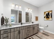 Thumbnail 29 of 34 - A bathroom with a large mirror, a sink, and a toilet.