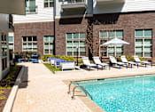 Thumbnail 50 of 57 - Decatur, GA, Apartments near Emory - Arlo - Swimming Pool With Clear Blue Water, Pool Ladder, Lounge Chairs, Umbrella Shade, And Apartment Building Windows Surrounding The Deck.