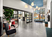 Thumbnail 33 of 57 - a lobby with chairs and a plant and glass doors