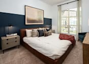 Thumbnail 13 of 57 - 1-Bedroom Apartments in Decatur, GA - Arlo Decatur - Bedroom With Bed, Nightstands with Lamps, Dresser, Armchair, Plush Carpet, Accent Wall,  Framed Wall Art, and Large Window With Blinds and Coverings