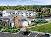 Thumbnail 34 of 35 - A large white building with a grey roof and a brick chimney is surrounded by a parking lot.