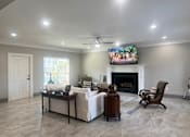 Thumbnail 17 of 23 - A living room with a fireplace and a television mounted above it.
