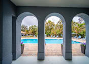 Thumbnail 6 of 43 - A pool area is seen through a window with three arches.