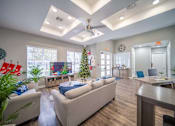 Thumbnail 11 of 43 - A living room with a couch, a Christmas tree, and a ceiling fan.