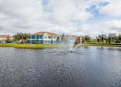 Thumbnail 39 of 43 - A fountain in the middle of a lake with houses in the background.