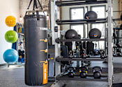 Thumbnail 40 of 71 - a gym with a punching bag and weights on a rack