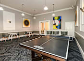 Thumbnail 11 of 36 - a ping pong table in a room with chairs and paintings