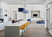 Thumbnail 4 of 36 - a kitchen with a long white counter and yellow chairs