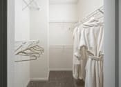 Thumbnail 18 of 36 - a walk in closet with a robe and clothes rack