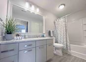 Thumbnail 16 of 24 - A bathroom with a white toilet, a sink, and a shower.