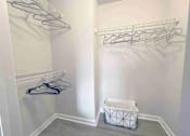 Thumbnail 17 of 24 - A white closet with clothes hangers and a basket.