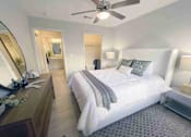 Thumbnail 15 of 24 - Greenville, SC, Luxury Apartments Near Libery Bridge - The Aventine Greenville - A Bedroom With A White Upholstered Bed, Grey Pillows, And A View Into A Walk-In Closet And En-Suite Bathroom.