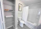 Thumbnail 19 of 24 - A white bathroom with a toilet, a tub, and a refrigerator.