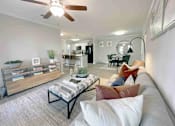 Thumbnail 13 of 24 - Greenville, SC Luxury Apartments With In-Unit Washer And Dryer - The Aventine Greenville - A Living Room And Dining Area With A Grey Sofa, Pillows, Wood-Style Flooring, And A View Into A Kitchen.