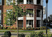 Thumbnail 19 of 20 - A modern building with a curved design and a lamp post in front.