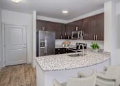 Thumbnail 2 of 20 - Charlotte, NC, Apartments Near Charlotte Premium Outlets - Gramercy Square at Ayrsley - Kitchen with Breakfast Bar, Bar Chairs, Stainless Steel Appliances, and Luxury Vinyl Plank Flooring.