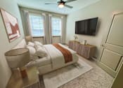 Thumbnail 31 of 54 - A bedroom with a bed, a ceiling fan, and a television.