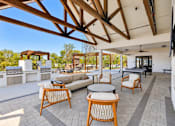 Thumbnail 22 of 29 - A patio with a white couch and wooden chairs.