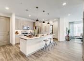 Thumbnail 14 of 30 - A modern kitchen with a white island and bar stools.