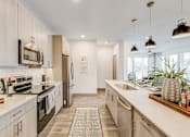 Thumbnail 13 of 30 - Luxury Apartments in Fort Worth, TX, with In-Unit Washer and Dryer - The Union at River East - Kitchen with Breakfast Bar, Quartz Countertops, Stainless Steel Appliances, and Pendant Lighting.