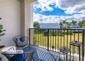 Thumbnail 26 of 78 - a balcony with chairs and a table and a view of a field and a house at Altis Blue Lake, Florida, 33467