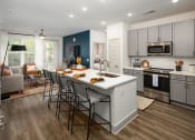 Thumbnail 1 of 70 - Apartments for Rent in Belmont, NC - Banks at Mt. Holly - Open-Concept Kitchen with Wood-Inspired Plank Flooring, Island/Breakfast Bar with Seating, Stainless-Steel Appliances, Quartz Countertops, Subway Tile Backsplash, Grey Cabinets, and Access to Living Area