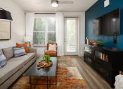 Thumbnail 7 of 70 - 2-Bedroom Apartments in Belmont, NC- The Banks Apartments - Living Room with Wood-Inspired Plank Flooring, Area Rug, Sofa, Coffee Table, Armchair, Ceiling Fan, Storage Cabinet, Wall-Mounted TV, Window, and Glass Door with Access to Private Balcony.