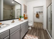 Thumbnail 10 of 70 - Belmont, NC Apartments - The Banks Apartments - Bathroom with Quartz Vanity Countertop, Large Vanity Mirror, Sliding Glass Door to Stand up Shower, and Attached Spacious Closet.