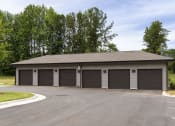 Thumbnail 55 of 70 - Apartments in Belmont, NC, for Rent - The Banks Apartments - Private Garages with Roll-Up Doors, Driveway, and Trees in the Background.