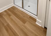 Thumbnail 18 of 35 - A white tiled shower with a glass door is in a room with wood flooring.