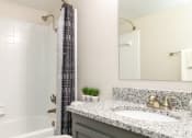 Thumbnail 16 of 31 - a bathroom with a shower and a sink and a mirror