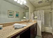 Thumbnail 11 of 35 - A bathroom with a sink, mirror, and shower.