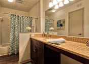 Thumbnail 13 of 35 - A bathroom with a patterned shower curtain and a sink with a brown counter top.