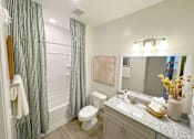 Thumbnail 15 of 23 - A bathroom with a toilet, sink, and shower curtain.
